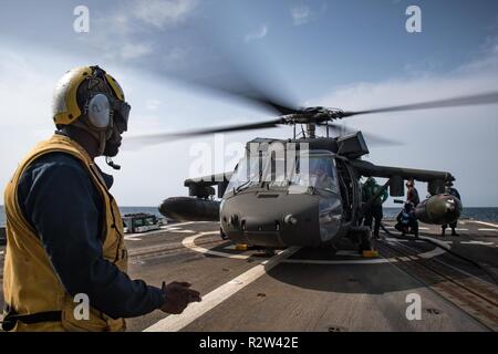 ARABIAN GULF (Nov. 7, 2018) Boatswain’s Mate 2nd Class Archangel Smiley signals for U.S. Navy Sailors refueling a U.S. Army UH-60 Black Hawk helicopter, assigned to “Shiner” of 1st Battalion, 108th Aviation Regiment, on the flight deck of the guided-missile destroyer USS Jason Dunham (DDG 109). Jason Dunham is deployed to the U.S. 5th Fleet area of operations in support of naval operations to ensure maritime stability and security in the Central Region, connecting the Mediterranean and the Pacific through the western Indian Ocean and three strategic choke points. Stock Photo