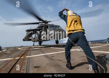 ARABIAN GULF (Nov. 7, 2018) Boatswain’s Mate 2nd Class Archangel Smiley signals a U.S. Army UH-60 Black Hawk helicopter, assigned to “Shiner” of 1st Battalion, 108th Aviation Regiment, to lift off from the flight deck of the guided-missile destroyer USS Jason Dunham (DDG 109). Jason Dunham is deployed to the U.S. 5th Fleet area of operations in support of naval operations to ensure maritime stability and security in the Central Region, connecting the Mediterranean and the Pacific through the western Indian Ocean and three strategic choke points. Stock Photo