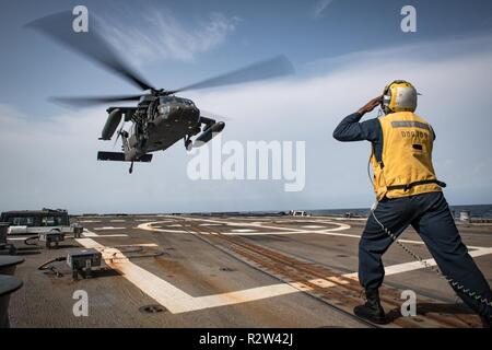 ARABIAN GULF (Nov. 7, 2018) Boatswain’s Mate 2nd Class Archangel Smiley signals for a U.S. Army UH-60 Black Hawk helicopter, assigned to “Shiner” of 1st Battalion, 108th Aviation Regiment, to land on the flight deck of the guided-missile destroyer USS Jason Dunham (DDG 109). Jason Dunham is deployed to the U.S. 5th Fleet area of operations in support of naval operations to ensure maritime stability and security in the Central Region, connecting the Mediterranean and the Pacific through the western Indian Ocean and three strategic choke points. Stock Photo