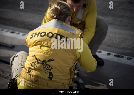 ATLANTIC OCEAN (Nov. 10, 2018) Lt. Cmdr. Bethany Harrison, from Kansas City, Missouri, ties her boots to a catapult before launching them from the aircraft carrier USS George H.W. Bush (CVN 77). Navy catapult officers traditionally launch their boots at the end of a successful tour. GHWB is underway in the Atlantic Ocean conducting routine training exercises to maintain carrier readiness. Stock Photo