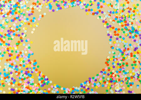Round frame of colorful confetti on yellow background. Stock Photo