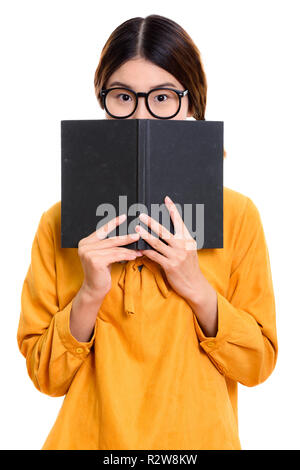 Young beautiful Asian woman hiding behind book Stock Photo