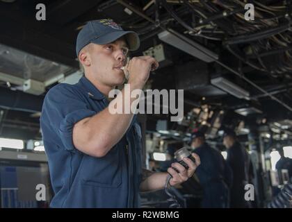 ATLANTIC OCEAN (Nov. 15, 2018) Boatswain’s Mate 3rd class Jacob Mcbroom, from Houston, pipes the ships whistle from the piolet house of the Arleigh Burke-class guided-missile destroyer USS Ramage (DDG 61) in the 1MC before passing a message to the crew. Ramage is currently underway in the U.S. 4th Fleet area of responsibility in support of U.S. 4th Fleet tasking. Stock Photo