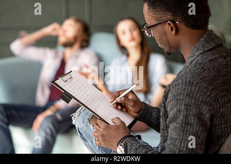 African ethnicity psychologist making psychological test sitting with young couple in the green office Stock Photo