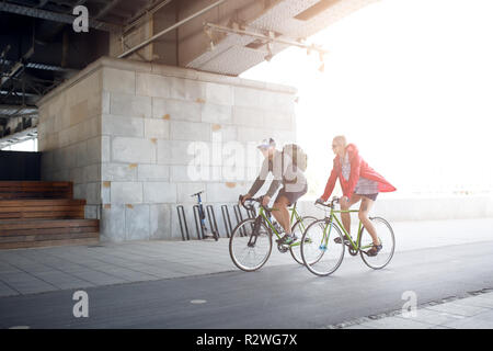 Side image of sportive woman and man riding bike through underpass Stock Photo