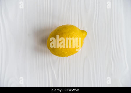 Single whole lemon on white wooden surface close Stock Photo