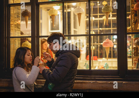 London, UK - February, 2019. A young couple eating an ice cream outside a shop in Covent Garden. Stock Photo