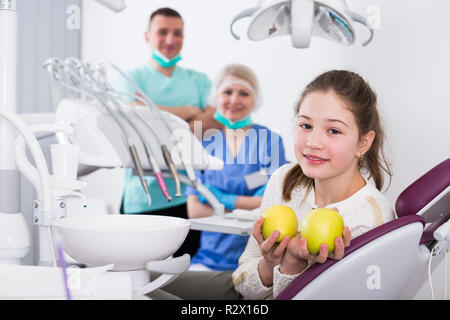 Portrait of happy teen girl in modern dental clinic with fresh apples in hands Stock Photo