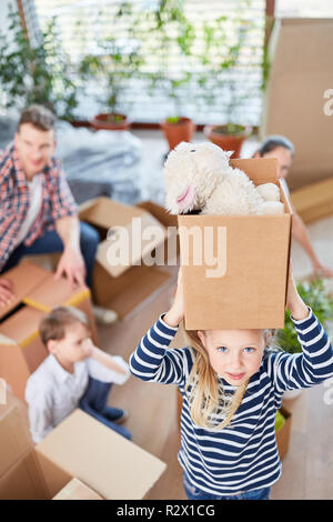 Little girl carries cardboard with her stuffed animal when moving to the new house Stock Photo