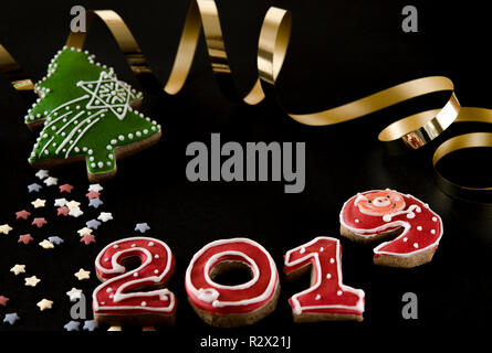 New Year card on black background gingerbread red numbers 2019 with multi-colored stars, green gingerbread fir and gold streamer Stock Photo