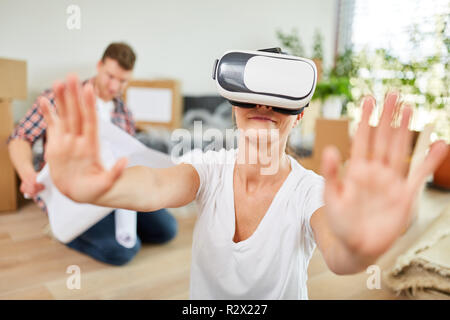 Young woman with innovative VR glasses looks for orientation after moving Stock Photo