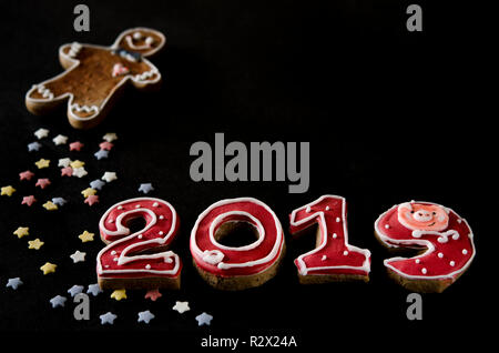New Year card on black background gingerbread red numbers 2019 with multi-colored stars and gingerbread Man Stock Photo