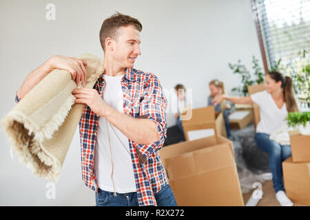 Man carries a carpet while moving with family in a new apartment Stock Photo