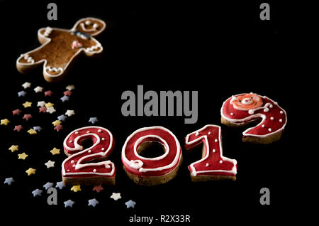 New Year card on black background gingerbread red numbers 2019 with multi-colored stars and gingerbread Man Stock Photo