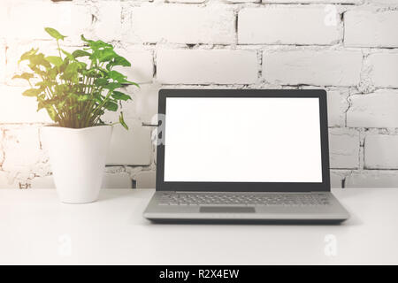 laptop with blank screen in front of white brick wall Stock Photo