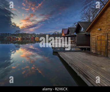 Tata, Hungary - Beautiful sunset over lake Derito (Derito to) in November with wooden fishing cottages and colourful sky and clouds Stock Photo