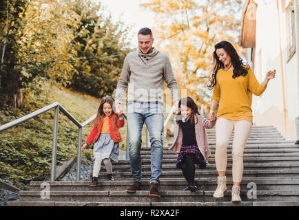 A young family with children walking down the stairs outdoors in town in autumn. Stock Photo