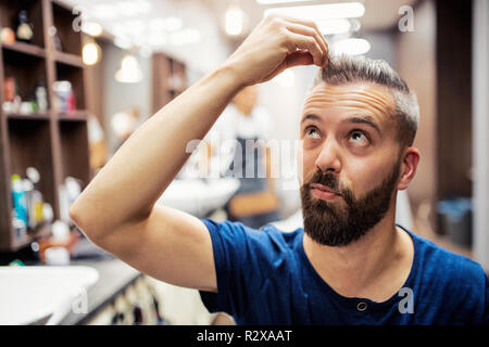 Hipster man client visiting haidresser and hairstylist in barber shop. Stock Photo