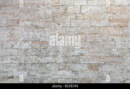 Wall of white and gray adarce travertine stone brick blocks, close up background texture, side view Stock Photo