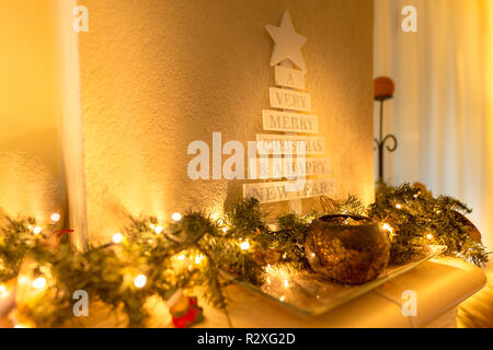 Christmas tree with vintage decorations near fireplace, led lights, golden decoration for Christmas Stock Photo
