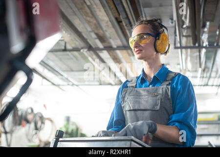 Woman worker operating a machine tool in metal workshop or facto Stock Photo