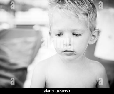 Portrait of caucasian white baby boy with chocolate on his face,black and white photo. Stock Photo