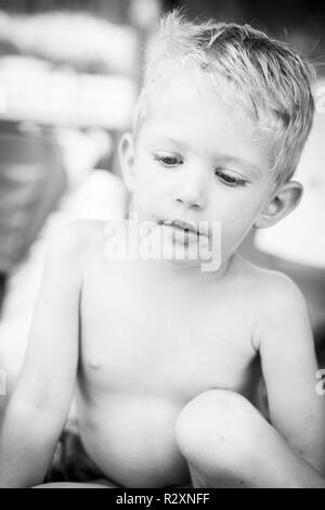 Portrait of caucasian white kid boy with chocolate on his face,vertical frame,black and white photo. Stock Photo