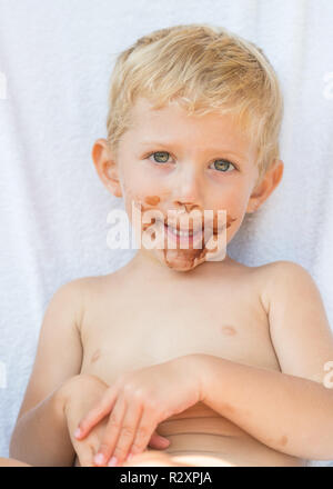 Portrait of fair-haired baby boy with chocolate on his face isolated on white background. Stock Photo