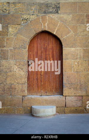 Old wooden door and window framed by arched bricks stone wall at the courtyard of al Razzaz historic house, Darb al Ahmar district, Old Cairo, Egypt Stock Photo