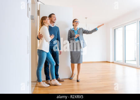 Realtor showing house to a young couple Stock Photo