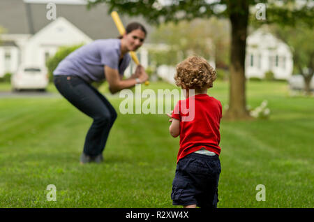 Young boy playing baseball with his mother in a back yard. Stock Photo