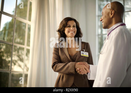 Two doctors shaking hands and smiling at each other. Stock Photo