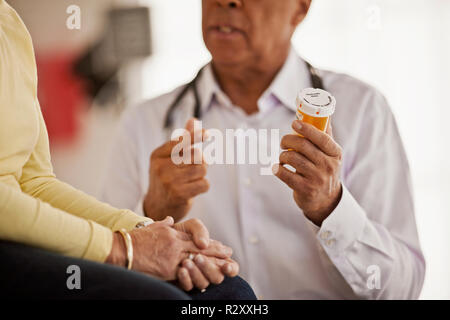Pill bottle being held by a male doctor as he has a conversation with a female doctor. Stock Photo