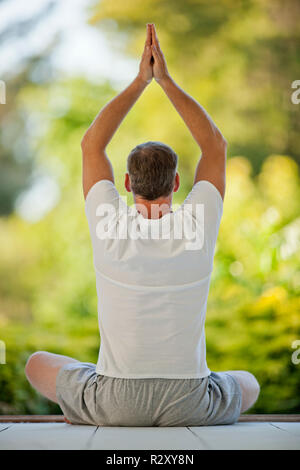 Relaxed middle aged man meditating on a deck. Stock Photo