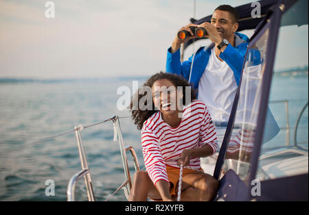 Happy young couple having fun with binoculars while sailing. Stock Photo