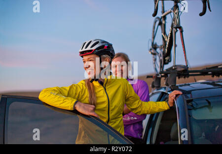 Smiling young women take one last look at the view of the sunset before they head home after a day of cycling in the countryside. Stock Photo
