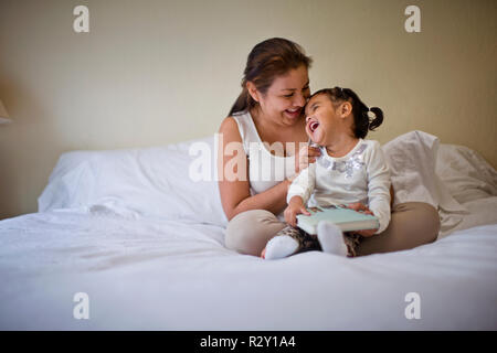 Happy young mother playfully tickling her toddler daughter. Stock Photo
