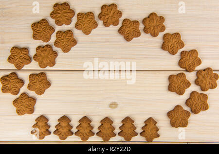 Christmas or New Year gingerbread cookies with snowflakes framed on brown sack background texture. Stock Photo