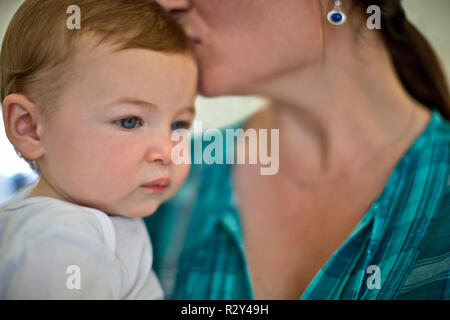 Mother giving her baby boy a kiss on the head. Stock Photo