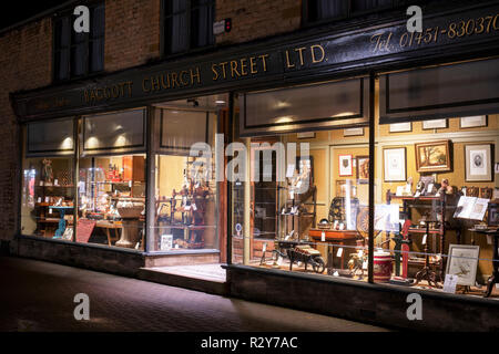 Baggott church street Ltd antiques shop window display at night. Stow on the Wold, Cotswolds, Gloucestershire, England Stock Photo