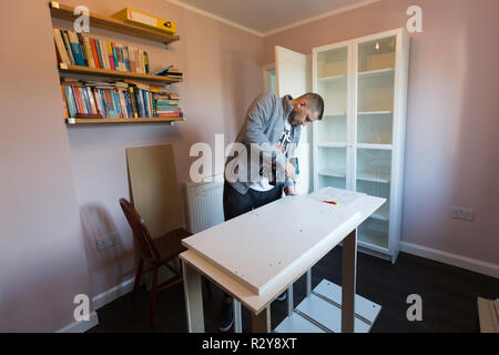 Man assembles an Ikea cupboard in a UK house. Stock Photo