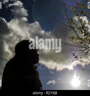 silhoette of figure with sun and clouds behind Stock Photo