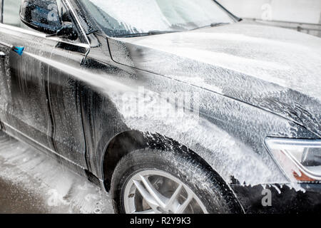 Close-up of a car under the water jet during the washing process on a self service car wash Stock Photo