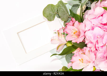 Mock up Composition of tender flowers and white frame in classic style. A gift for St. Valentine's Day with a place for your text. Flat lay, top view photo mock up Stock Photo
