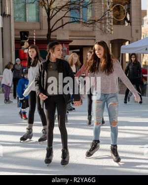 Reston VA -- November 17, 2018. A young woman and girl are ice skating together on the Reston Town Center rink; the young woman is helping the younger Stock Photo