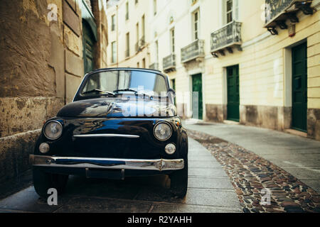 Black retro car parked on narrow italy street in Sardinia island. Classic automobile, travel background Stock Photo