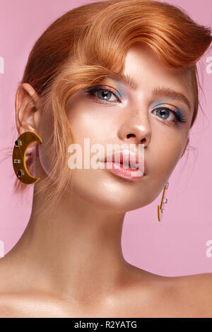 Beautiful girl with unusual accessories and make-up on a bright background. Beauty face. Stock Photo