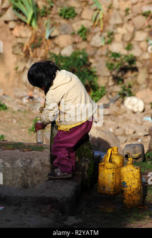Indigenous child filling plastic bottle with water from tap in Andean village, Bolivia Stock Photo