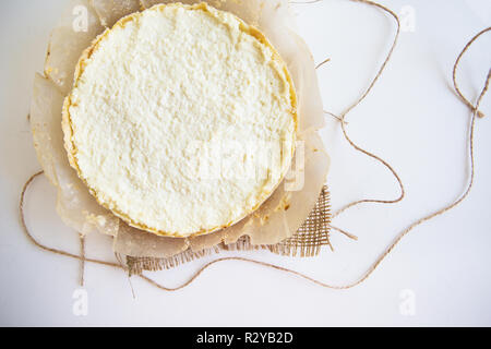 cheesecake on parchment stands on white table, close-up. Stock Photo