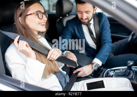 Businesman fastening belt to a woman worrying about her safety in the car Stock Photo